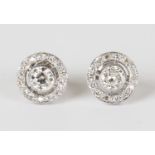 A pair of white gold and diamond earrings, each collet set with the principal circular cut diamond