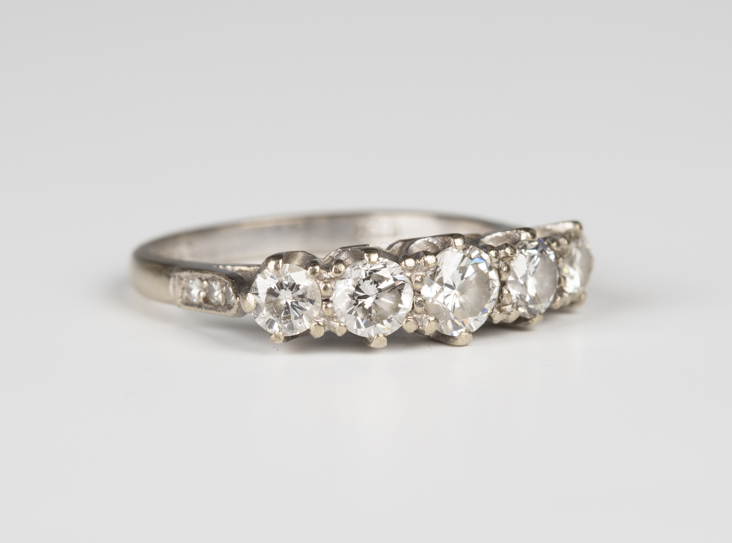A white gold and diamond five stone ring, claw set with a row of circular cut diamonds graduating in