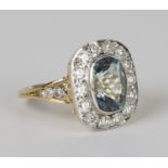 A gold, aquamarine and diamond ring, collet set with a cushion shaped aquamarine within a surround