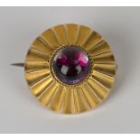 A Victorian gold and mauve foil backed cabochon gem set circular brooch with ridged decoration,