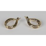 A pair of 9ct gold and diamond earrings, each in a twisted hoop shaped design, mounted with circular