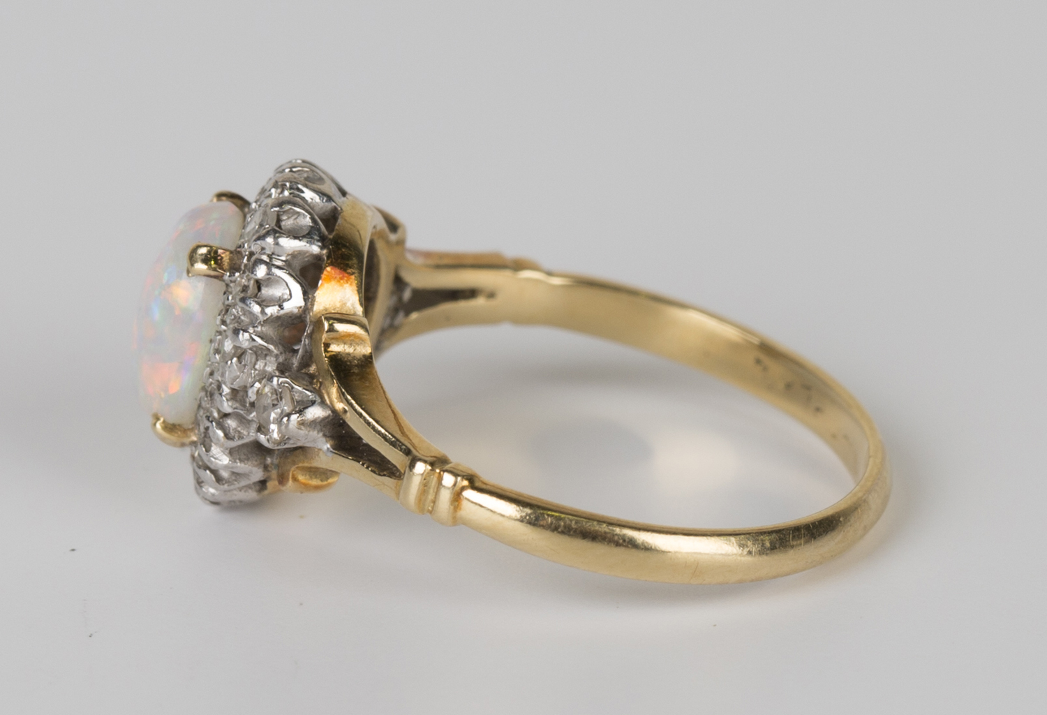 A gold, platinum, opal and diamond oval cluster ring, claw set with an oval opal within a surround - Image 2 of 3