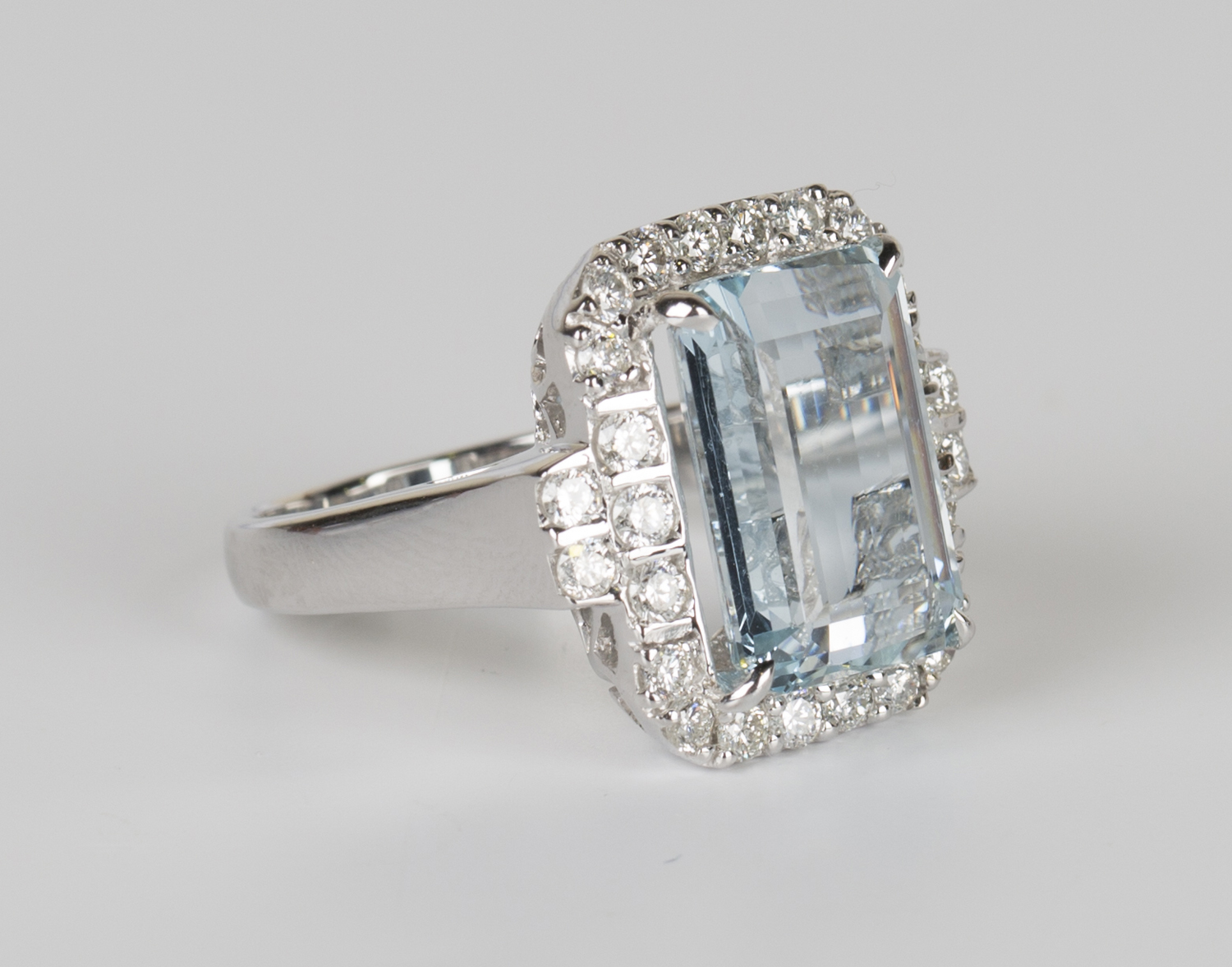 An 18ct white gold, aquamarine and diamond cluster ring, claw set with a rectangular cut