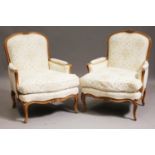 A pair of 20th century French walnut fauteuil armchairs with carved decoration, upholstered in