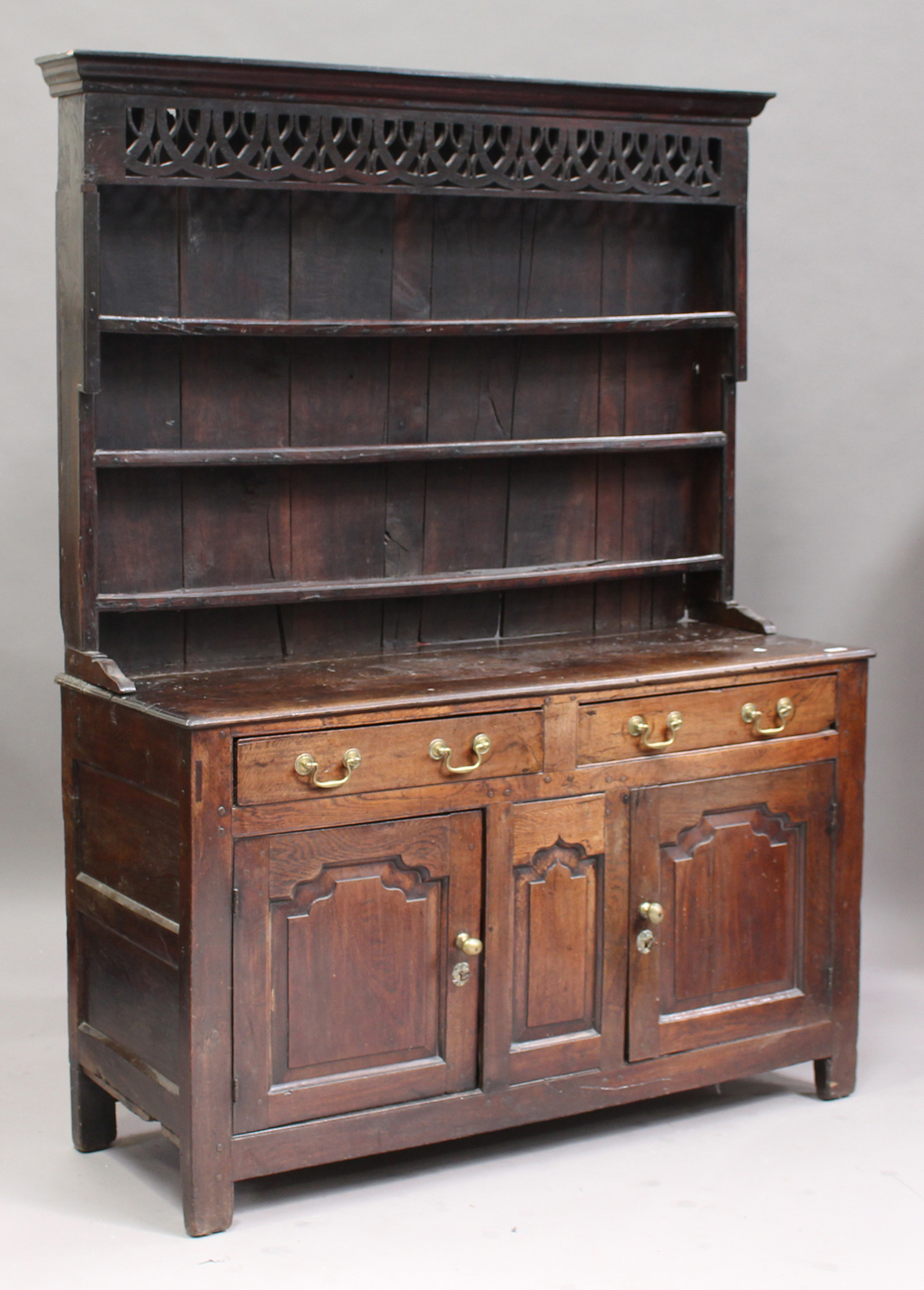 A George III oak dresser, the plate rack with a pierced fretwork frieze, the base fitted with two