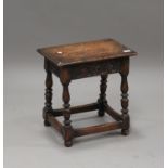 A 20th century Jacobean Revival oak joint stool with a carved frieze and turned legs, height 46cm,