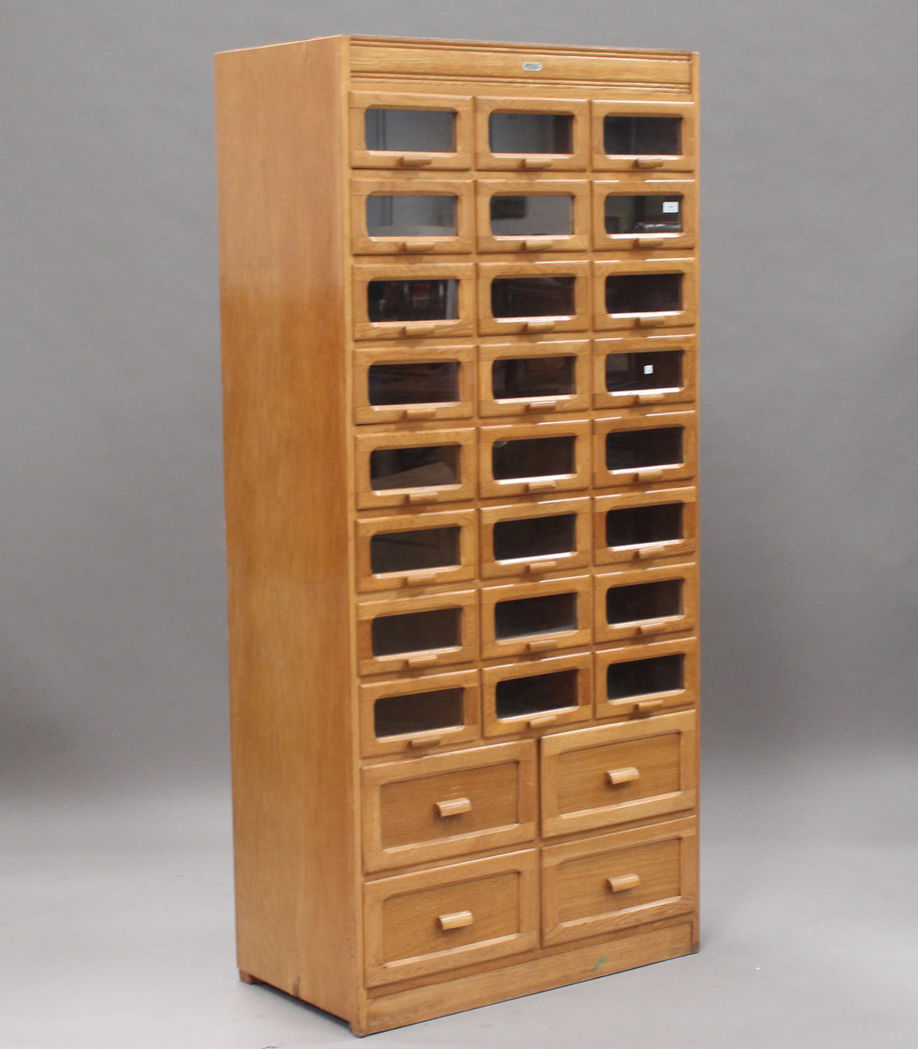 A mid-20th century pale oak haberdashery cabinet by Liddle, Keen & Co, London, fitted with twenty-