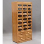 A mid-20th century pale oak haberdashery cabinet by Liddle, Keen & Co, London, fitted with twenty-