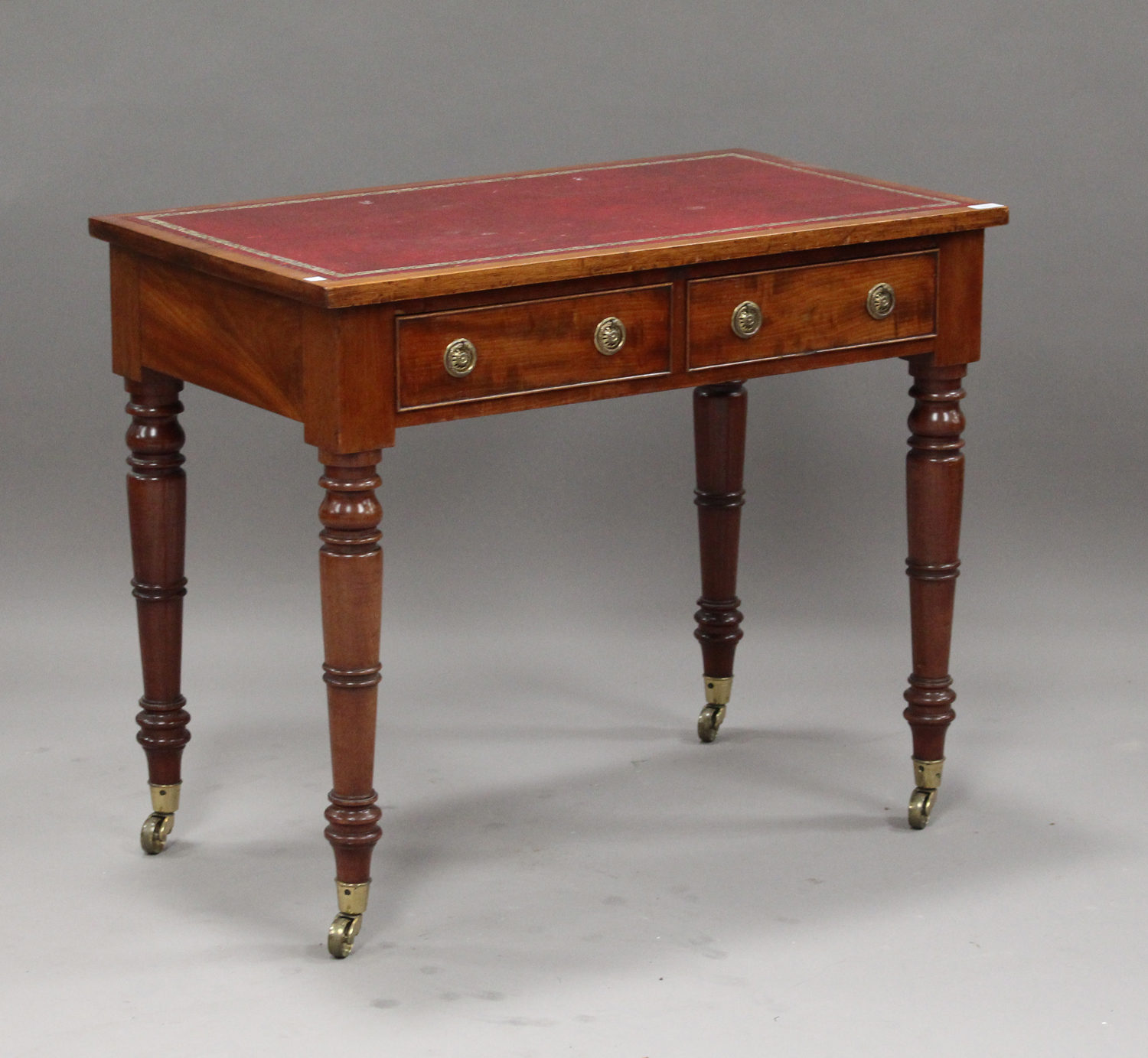 A Victorian mahogany writing table, the top inset with gilt-tooled red leather above two drawers, on