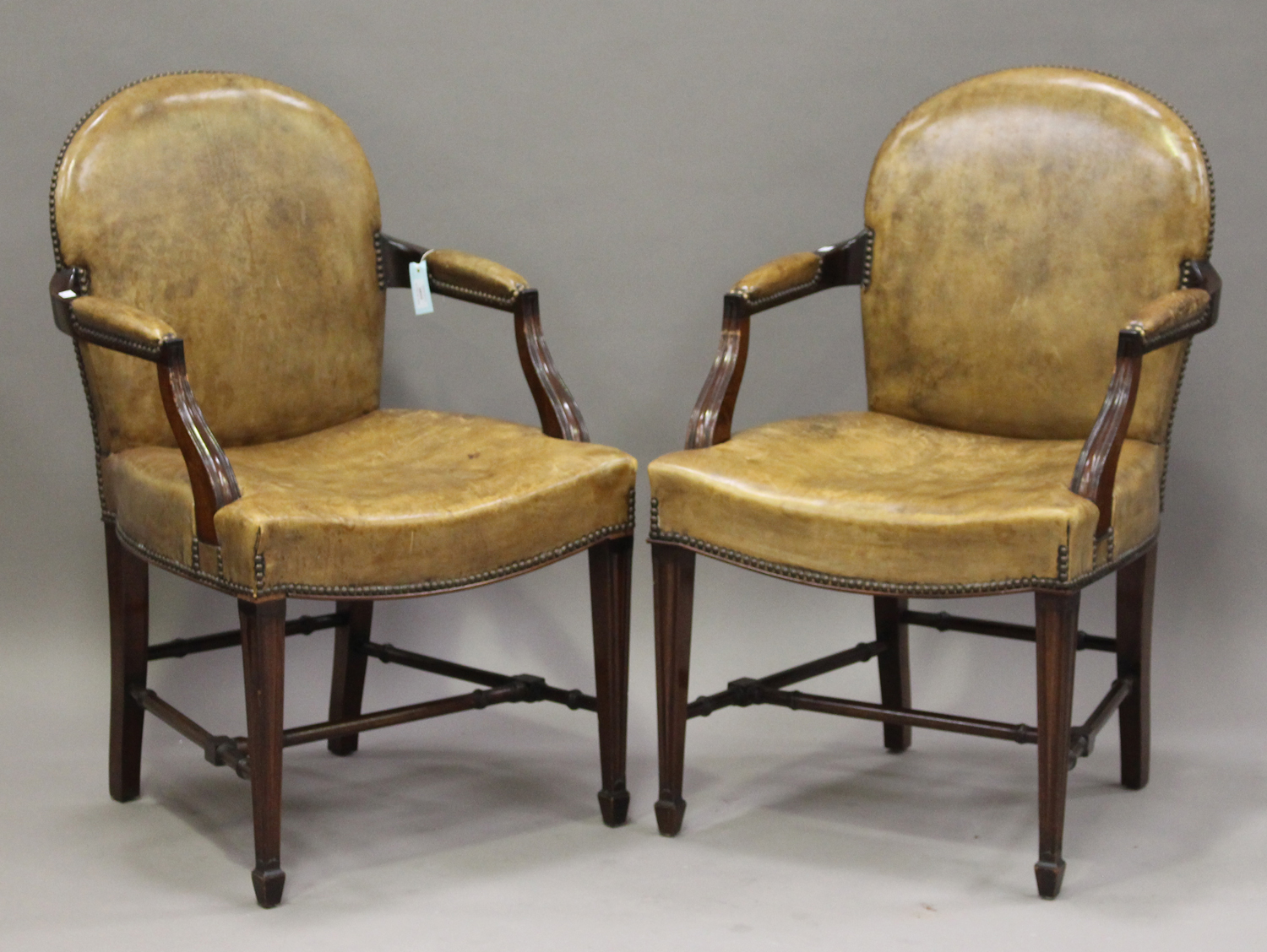 A pair of 20th century George III style tan leather and mahogany framed armchairs, the arched