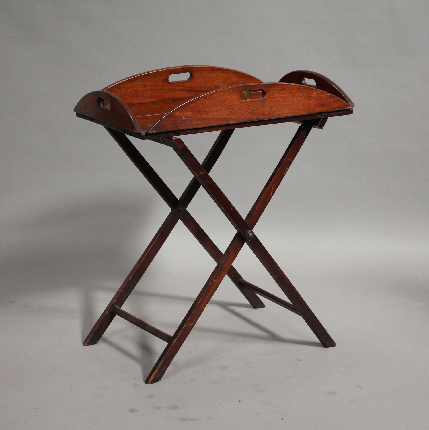 A 19th century mahogany butler's tray and folding stand with pierced handles and brass hinges,