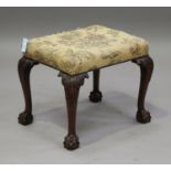 An early 20th century George III style mahogany stool, the overstuffed seat raised on carved