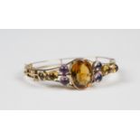 A gold, citrine and amethyst set oval hinged bangle, the front mounted with the principle oval cut