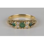 A gold, emerald and diamond ring, mounted with three circular cut emeralds alternating with two