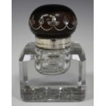 An early 20th century white metal mounted ebonized and cut glass inkwell, the domed hinged lid