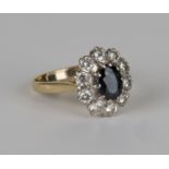 An 18ct gold, sapphire and diamond oval cluster ring, claw set with an oval cut sapphire within a