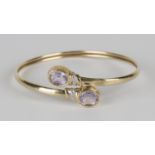 A 9ct gold, amethyst and diamond bangle, collet set with two oval cut pale amethysts and two small