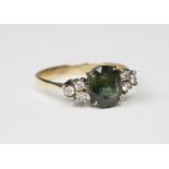 An 18ct gold, green sapphire and diamond ring, claw set with the oval cut green sapphire between