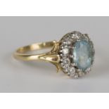 An aquamarine and diamond oval cluster ring, claw set with the oval cut aquamarine within a surround