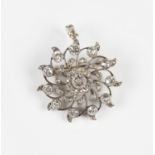 An Edwardian diamond pendant brooch in a circular swirling design, collet set with the principal