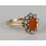 An 18ct gold, fire opal and diamond set oval cluster ring, claw set with the oval fire opal within a