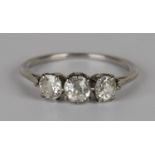 A diamond three stone ring, claw set with a row of cushion shaped diamonds, ring size approx K1/2,