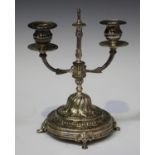 An Egyptian silver twin-branch candelabrum, raised on a domed foliate decorated circular base and