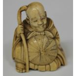 A Japanese carved ivory netsuke, Meiji period, modelled as a seated man wearing a long robe and