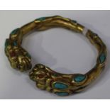 A Chinese gilt bronze bangle, cast with dragon head terminals and inset with turquoise and coral
