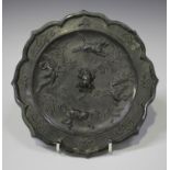 A Chinese silvered bronze mirror of foliate outline, one side cast with mythical beasts and