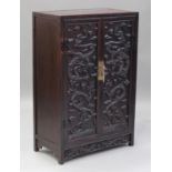 A Chinese hardwood two-door cabinet, early 20th century, each hinged rectangular door carved in