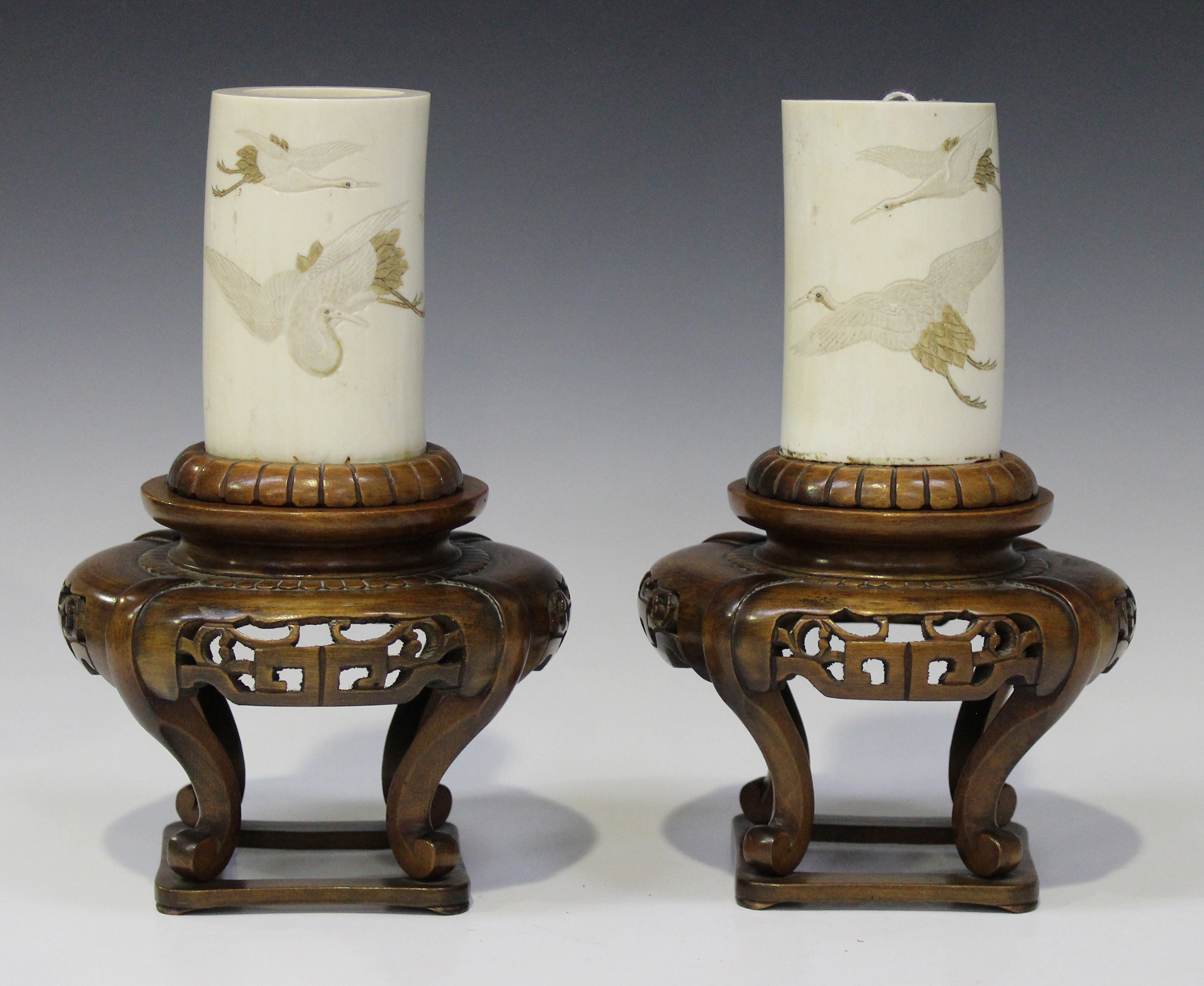 A pair of Japanese ivory tusk vases and wood stands, Meiji period, each tusk section incised and