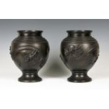 A pair of Japanese brown patinated bronze vases, Meiji period, each ovoid body cast in relief with a
