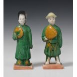 A pair of Chinese sancai glazed pottery figures of attendants, Ming dynasty, each modelled