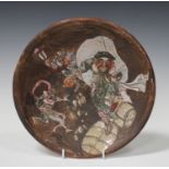 A Japanese earthenware circular dish, Meiji period, enamelled with a scene of Daikoku dancing upon