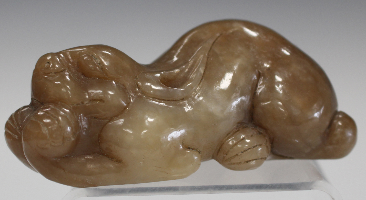 A Chinese brown jade carving, probably late 20th century, modelled as a recumbent crouching feline