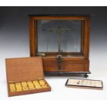 A set of early 20th century scientific balance scales within a glazed cabinet, width 41cm,
