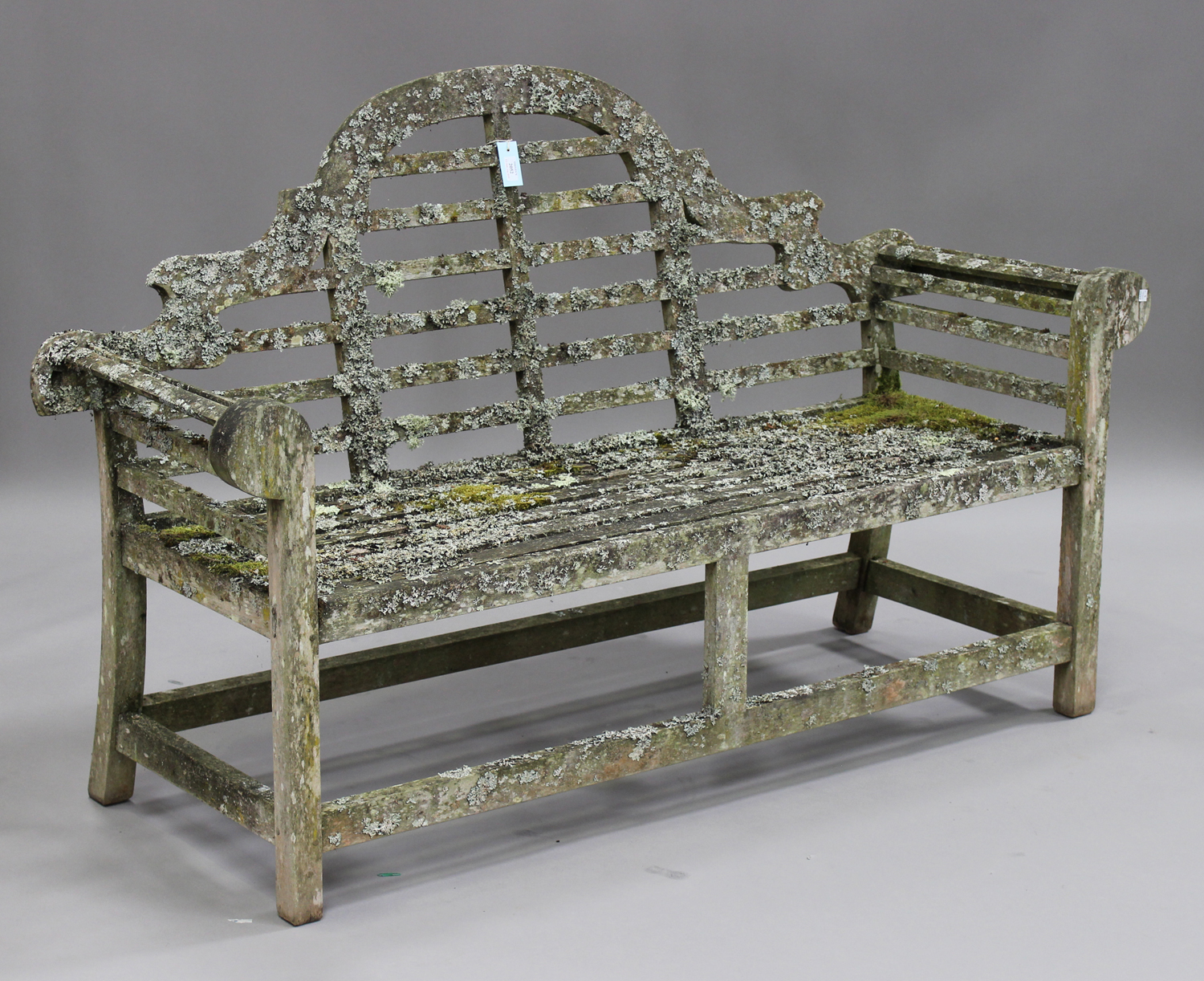 A 20th century teak garden bench, after a design by Sir Edwin Lutyens, the arched and slatted back