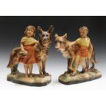 A pair of Art Deco style plaster figures, modelled as a boy and girl, with an Alsatian dog,