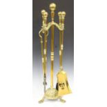 A late Victorian brass four-piece fire tool set and stand, the stem raised on a reeded dome base,