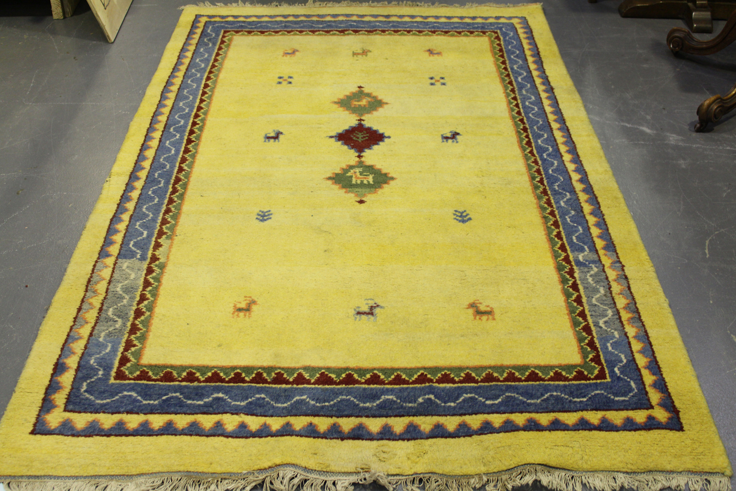 A Persian gabbeh rug, late 20th century, the sparsely decorated yellow field within a blue border,