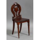 A late Victorian mahogany hall chair with carved and pierced decoration, the solid seat raised on