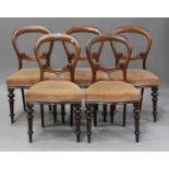 A set of five Victorian mahogany dining chairs, the overstuffed seats raised on turned legs,