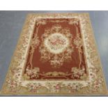 An Aubusson style flatweave rug, late 20th century, the terracotta field with a floral medallion,