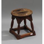 A 20th century oak stool, the circular pierced seat raised on turned and block legs united by
