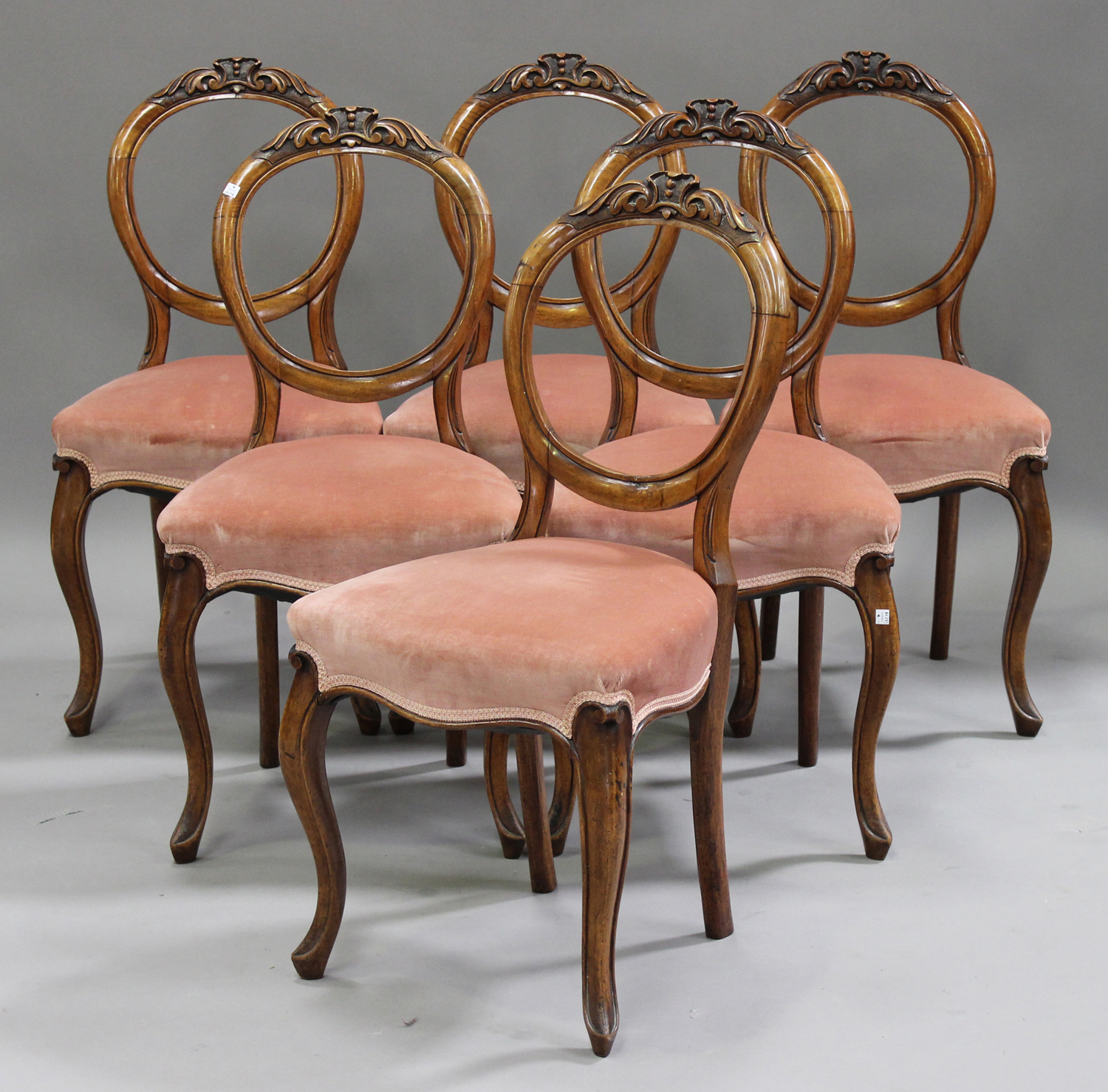 A set of six Victorian walnut spoon back dining chairs with carved decoration, the overstuffed seats