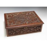An early 20th century carved walnut box, the hinged lid and sides decorated in relief with