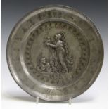 An 18th century pewter plate, cast with a central figure with dragon and infant, bearing impressed