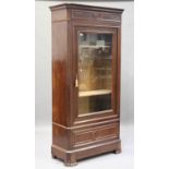 A late 19th century French walnut vitrine, the moulded pediment above an arch glazed door, the