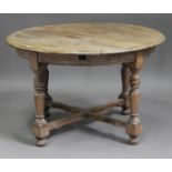 An early 20th century bleached oak extending circular dining table, the moulded top with two folding